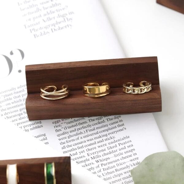 Gold rings displayed on a dark brown wooden ring display stand. Eco-friendly wood supplier for wholesale.