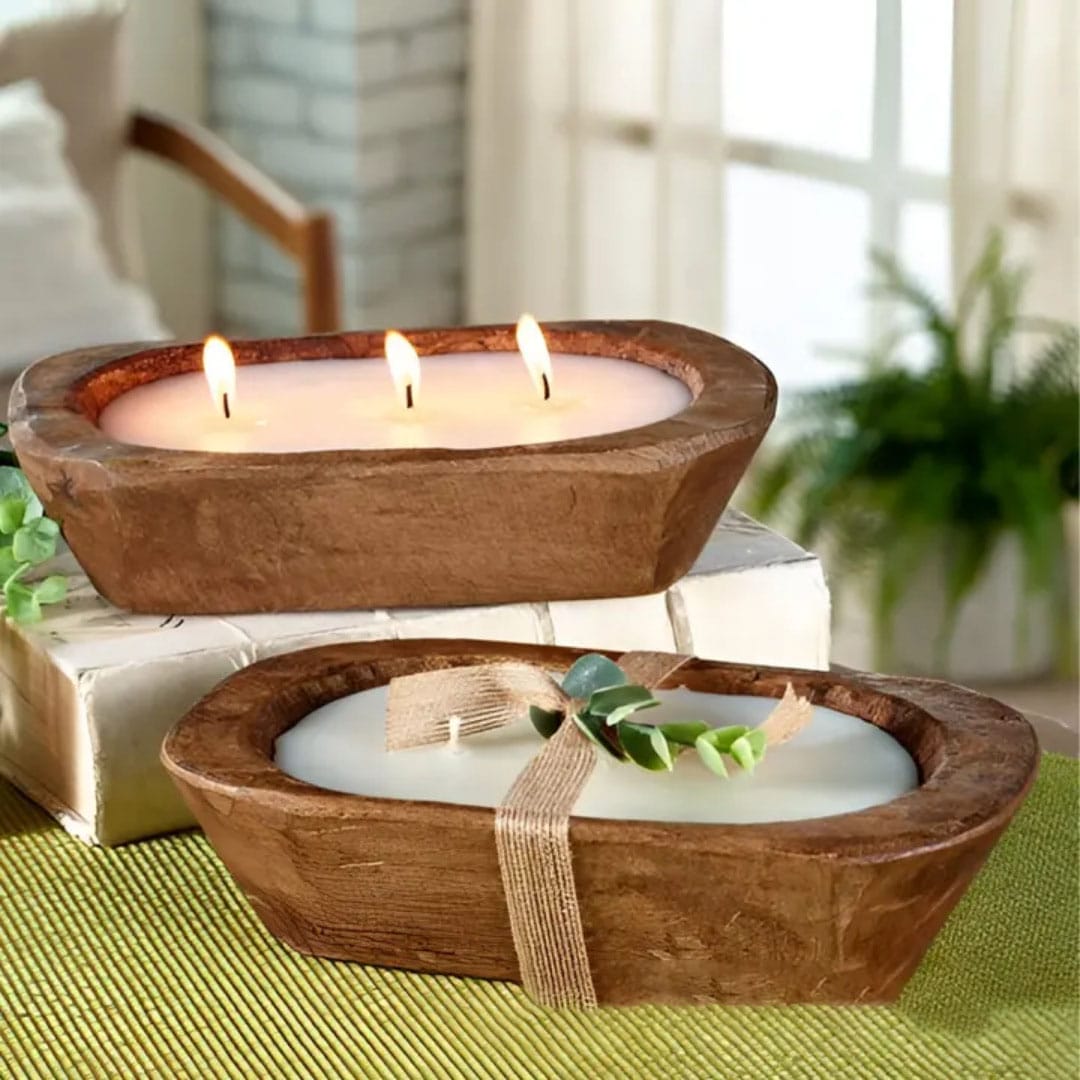 Two wooden candle holders are displayed; one is a lit trio-flame bowl, the other is unlit with a ribbon and green sprig—perfect scented candle trays to enhance cozy restaurant ambiance indoors.