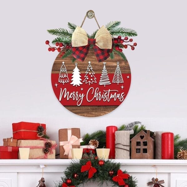 A round "Merry Christmas" sign, reminiscent of a wooden Christmas wreath with tree illustrations, hangs above a decorated mantle adorned with wrapped gifts, candles, garland, and holiday ornaments.