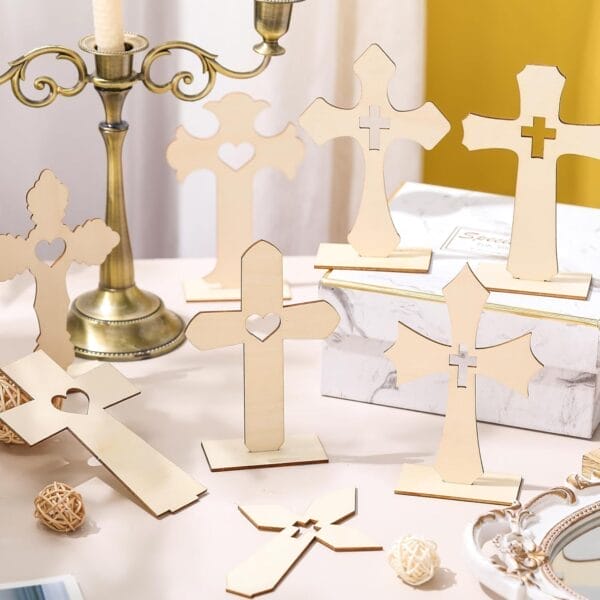Several unfinished custom wooden crosses with heart and cross cutouts are displayed upright on a table, surrounded by decorative items and a brass candle holder, perfect as unique cross decorations or thoughtful home decor.