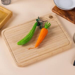 Rectangular wooden cutting board with a handle and vegetables.