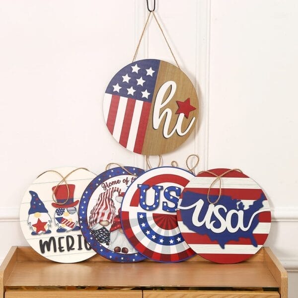 Five round, patriotic-themed wooden decor signs featuring American flag designs, stars, stripes, and text such as "hi," "USA," "MERICA," and "Home of the free" displayed on a wooden surface.