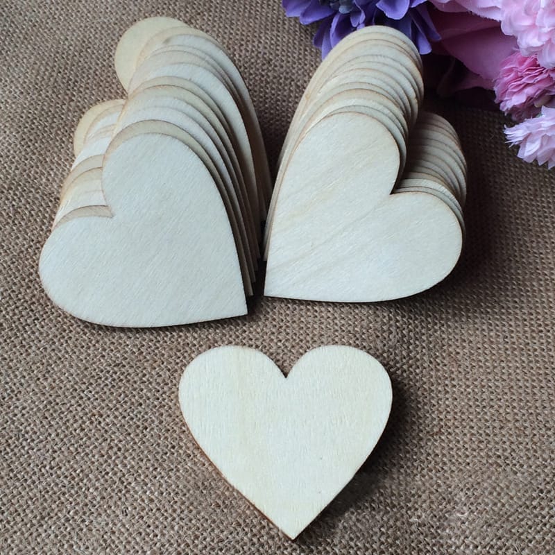Several thin, unfinished wooden heart shapes are stacked in two piles, with one wooden heart placed separately in the foreground on a burlap surface. Flowers are partially visible in the corner, perfect for hand-painted craft projects.