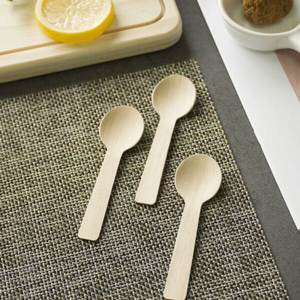 Three small wooden ice cream spoons on a placemat. Eco-friendly wholesale spoons.