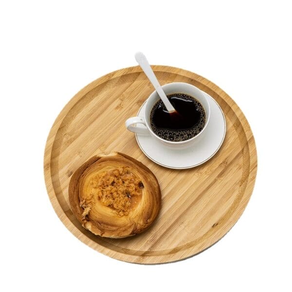A white cup of black coffee with a spoon and a pastry on a Wooden Serving Tray, viewed from above.