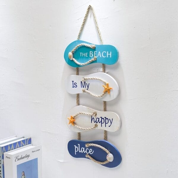 Mediterranean vintage signs inspire this beach wall decor, featuring four blue and white flip-flops arranged vertically with "The BEACH is my happy place" and two starfish accents.