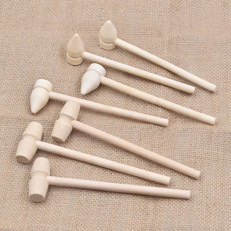 Eight small wooden mallets with cylindrical and tapered heads, perfect for wooden sticks crafts, are arranged on a textured brown fabric surface.