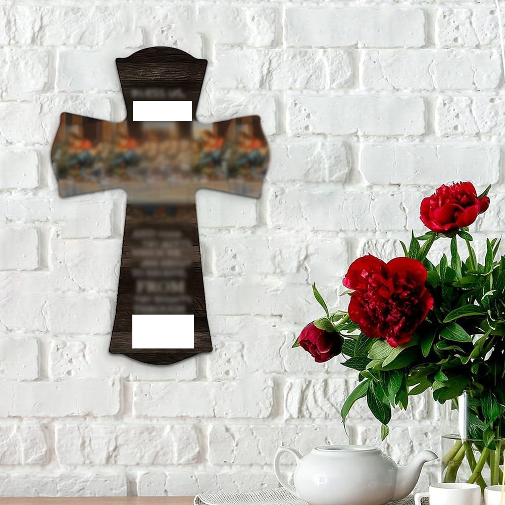 wooden wall crosses with blurred text hangs on a white brick wall above a table holding a white teapot and red flowers in a glass vase.