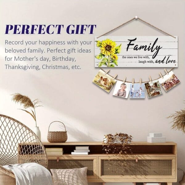 A wall sign with "Family" text, sunflower art, and hanging photos is displayed above a console table; this wooden wall decor makes a perfect gift for various occasions and is available from a wholesale manufacturer.