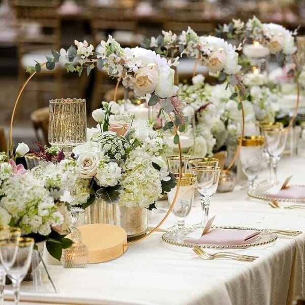 Elegant wedding reception tablescape with gold hoops, floral arrangements, and wooden bases. Wholesale wooden wreath supplier.