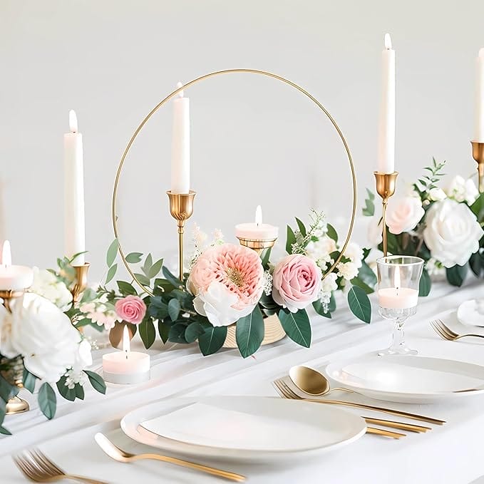Elegant wedding centerpiece with gold candlesticks, floral arrangement, and circular metal frame.
