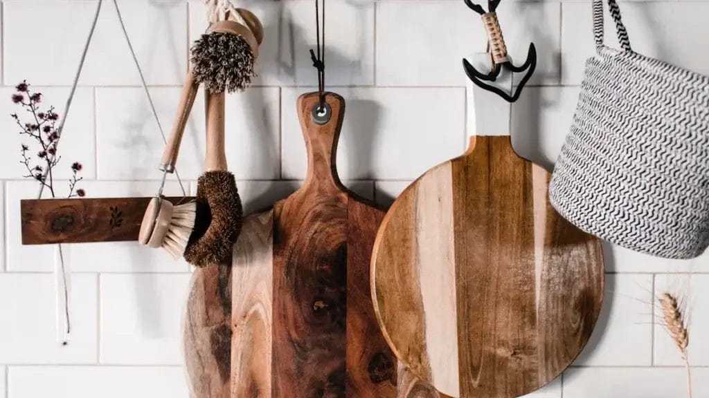 Wooden cutting boards and cleaning brushes hanging in a kitchen. Safe home sanitizing.