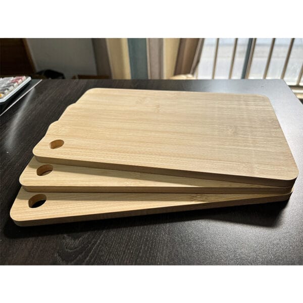 Three bamboo cutting boards stacked, showing a hole for hanging. Custom wooden cutting boards.