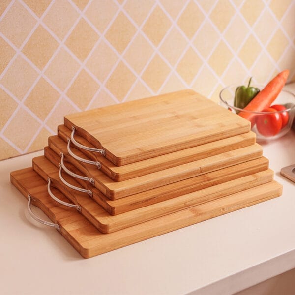 Stack of bamboo cutting boards with metal handles. Wholesale chopping boards.