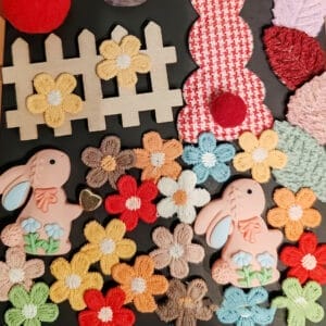 Assorted craft wood pieces: charming bunny figurines, colorful embroidered flowers, and a miniature picket fence. Perfect for crafting and DIY projects.