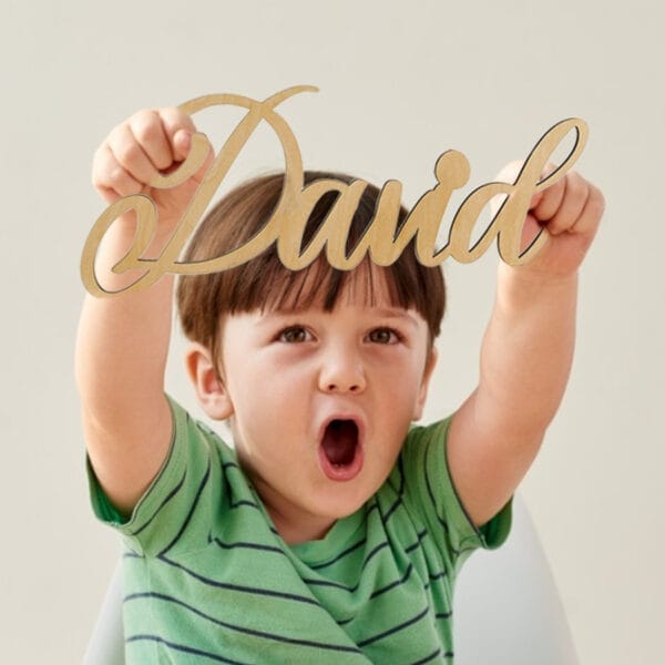 Happy toddler holding a custom wood name signs that says "David".