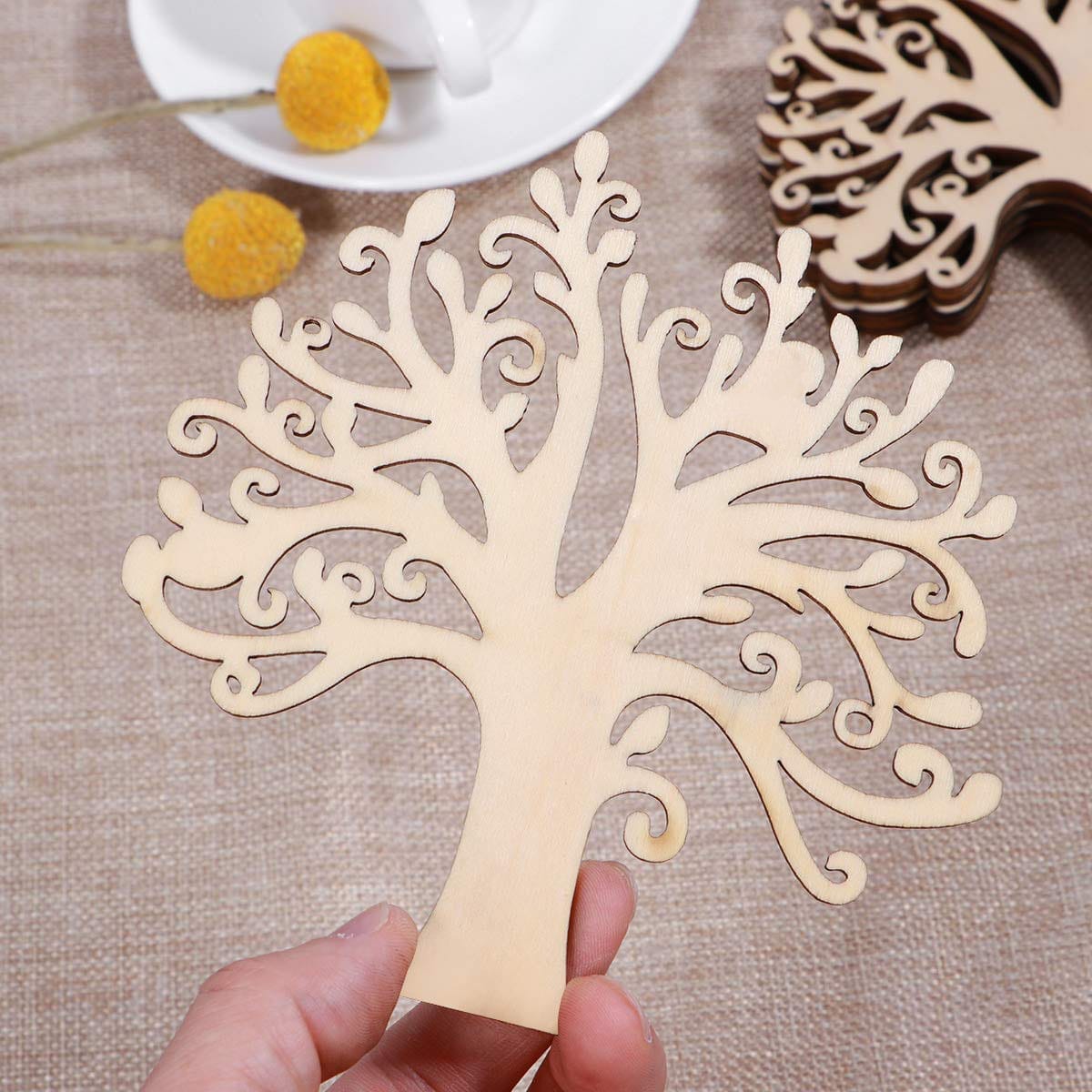 Hand holding ornate laser-cut wooden Christmas tree pendant. Custom wood pieces.