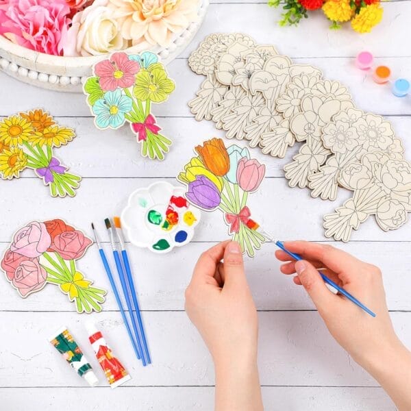 Person painting custom wooden flower cutouts with acrylic paints. DIY wood painting craft.