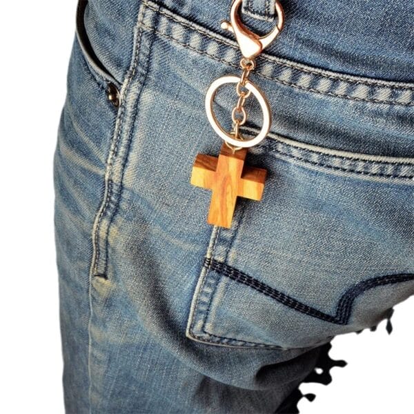 Olive wood cross keychain attached to jean pocket