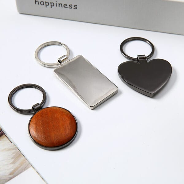 Three custom keychains: rectangular metal, heart-shaped metal, and round wooden. Custom wooden keychains available wholesale.