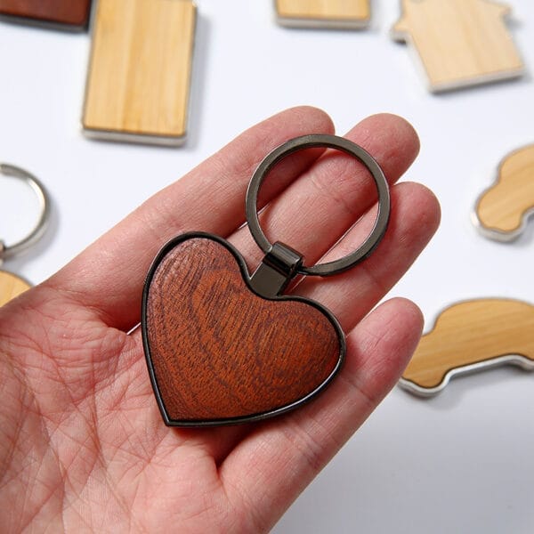 Hand holding a heart-shaped custom wooden keychain. Wholesale custom wooden keychains available.