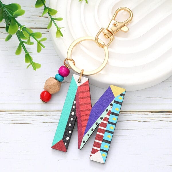 Colorful wooden letter M keychain with beads. Custom wooden word cutouts.