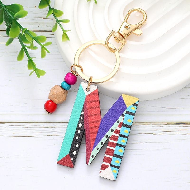 Colorful wooden letter M keychain with beads. Custom wooden word cutouts.