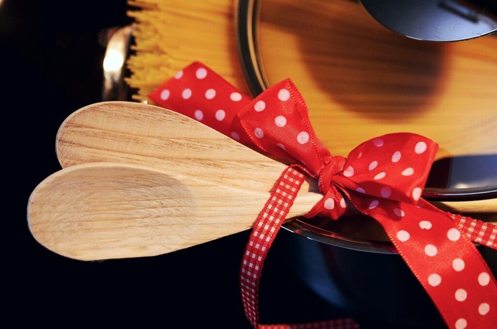 Wooden cooking spoons tied with a red polka dot ribbon on a pot.