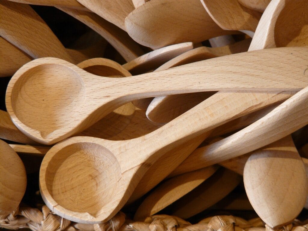 A pile of handcrafted wooden spoons in a woven basket.