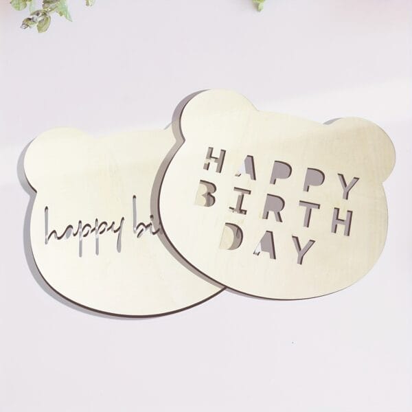Two laser-cut wooden bear head birthday decorations. One says "Happy Birthday," the other "Happy Bi".