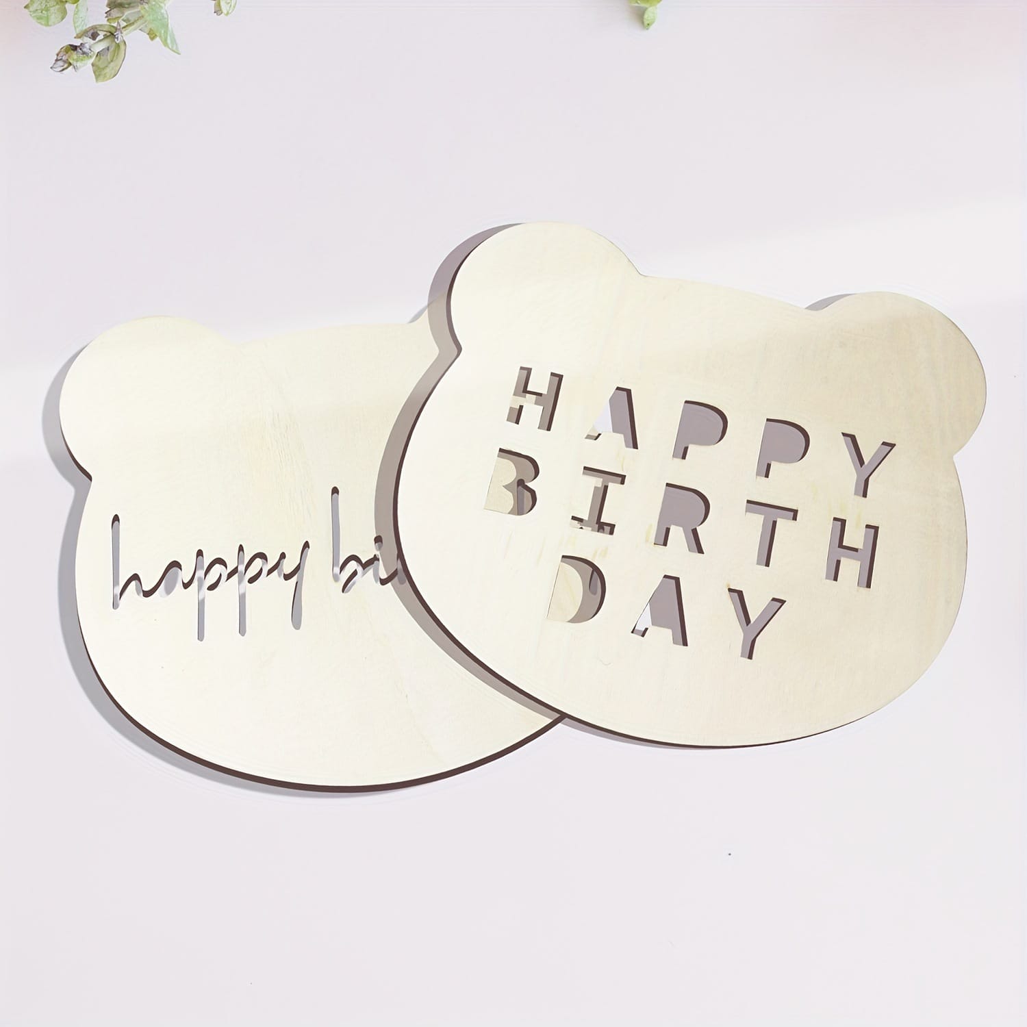 Two laser-cut wooden bear head birthday decorations. One says "Happy Birthday," the other "Happy Bi".