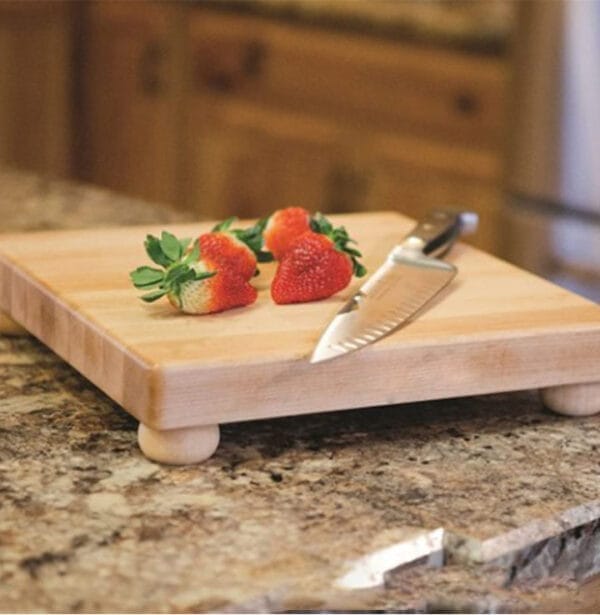 Wooden maple cutting board with feet, perfect for distributors. Features strawberries and a knife.