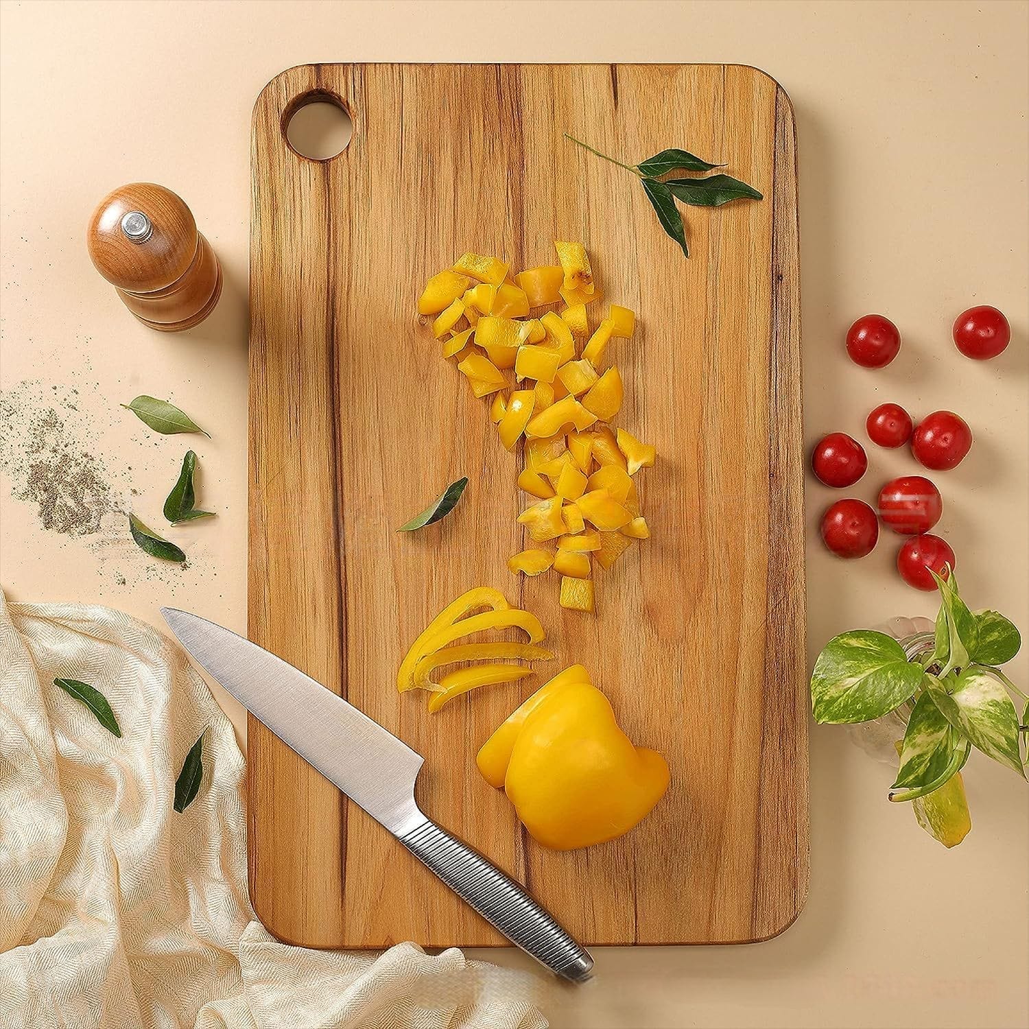 Wooden cutting board with chopped yellow bell peppers, knife, and herbs. Non toxic wood cutting board