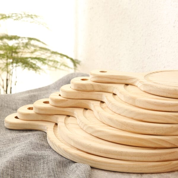 Stack of round pine wood pizza boards with handles. Wholesale supplier of restaurant pizza boards.