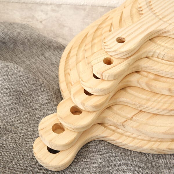 Stack of round pine wood pizza boards with handles. Wholesale pizza serving trays for restaurants.