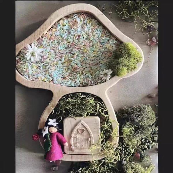 Wooden mushroom tray with colorful rice, moss, and fairy figurine.