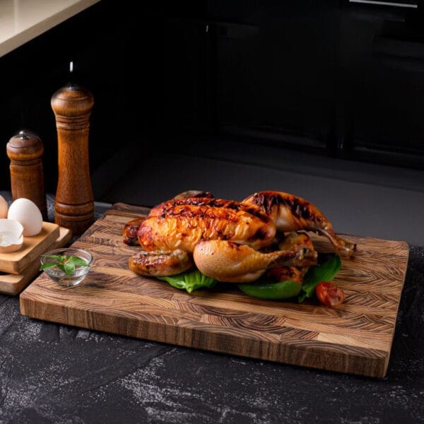 Roasted chicken on a rustic teak wood cutting board. Wholesale cutting boards available.