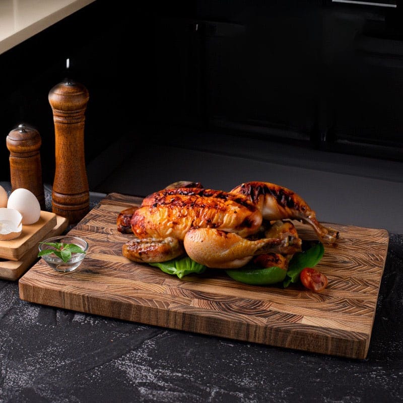 Roasted chicken on a rustic teak wood cutting board. Wholesale cutting boards available.