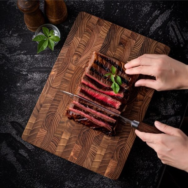 Sliced grilled steak on a beautiful teak wooden cutting board. Wholesale cutting boards available.