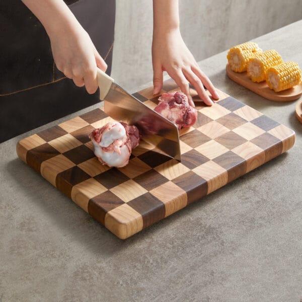 Person using a large, checkered walnut cutting board to cut meat. Wholesale kitchen boards.