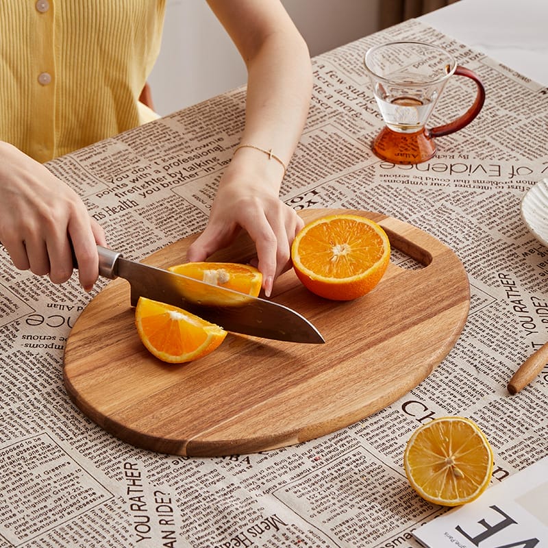 Acacia wood cutting board with oranges being sliced