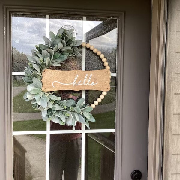 Wood bead wreath with lambs ear greenery and "hello" sign. Supplier of wooden bead door hangings.