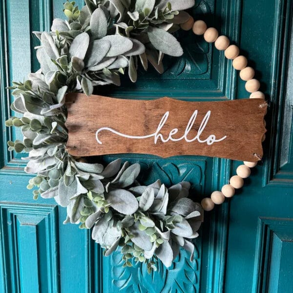 Wooden bead wreath with lambs ear greenery and "hello" sign. Supplier of wooden bead door hangings.