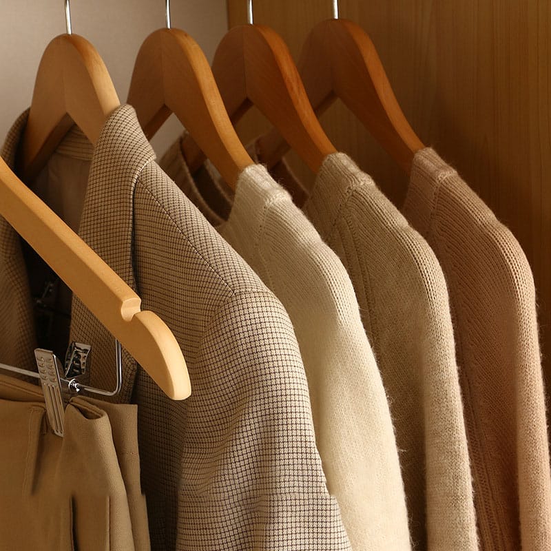 High-quality wooden coat hangers showcasing beige sweaters and a jacket; ideal for custom clothing storage solutions.