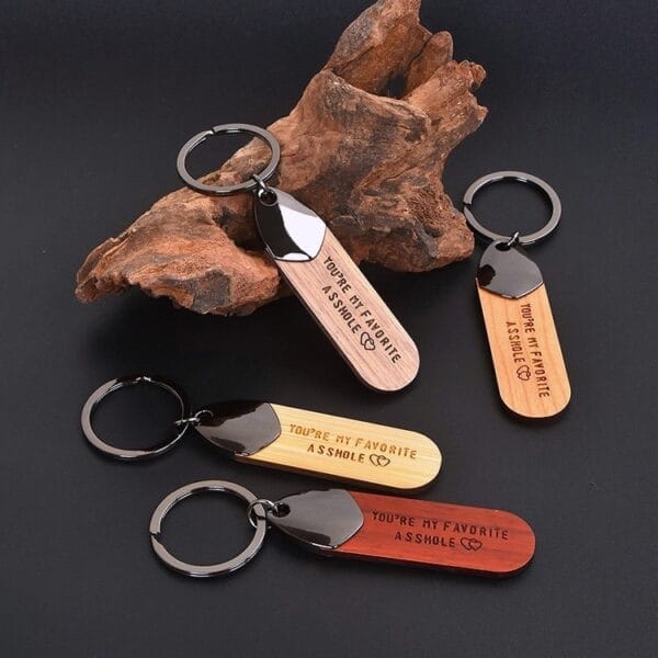 Three wooden keychains engraved "You're my favorite asshole". Wholesale wooden keychain supplier.