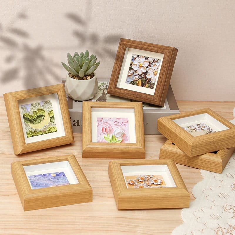 Six small wooden picture frames display various paper flower art.