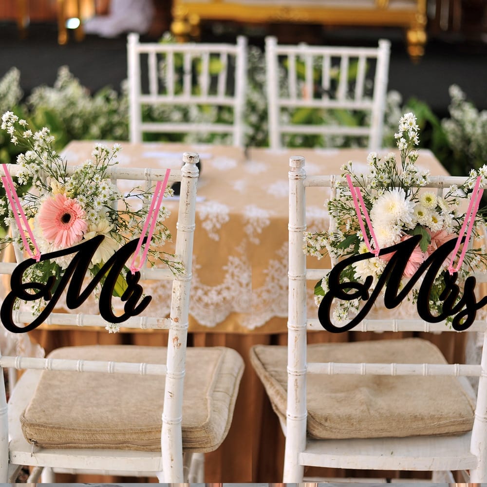 wood wedding signs chairs decorated with floral arrangements and custom "Mr." and "Mrs." wood signs.