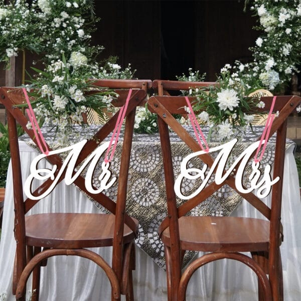 Wooden wedding chair signs reading "Mr" & "Mrs," adorned with flowers.