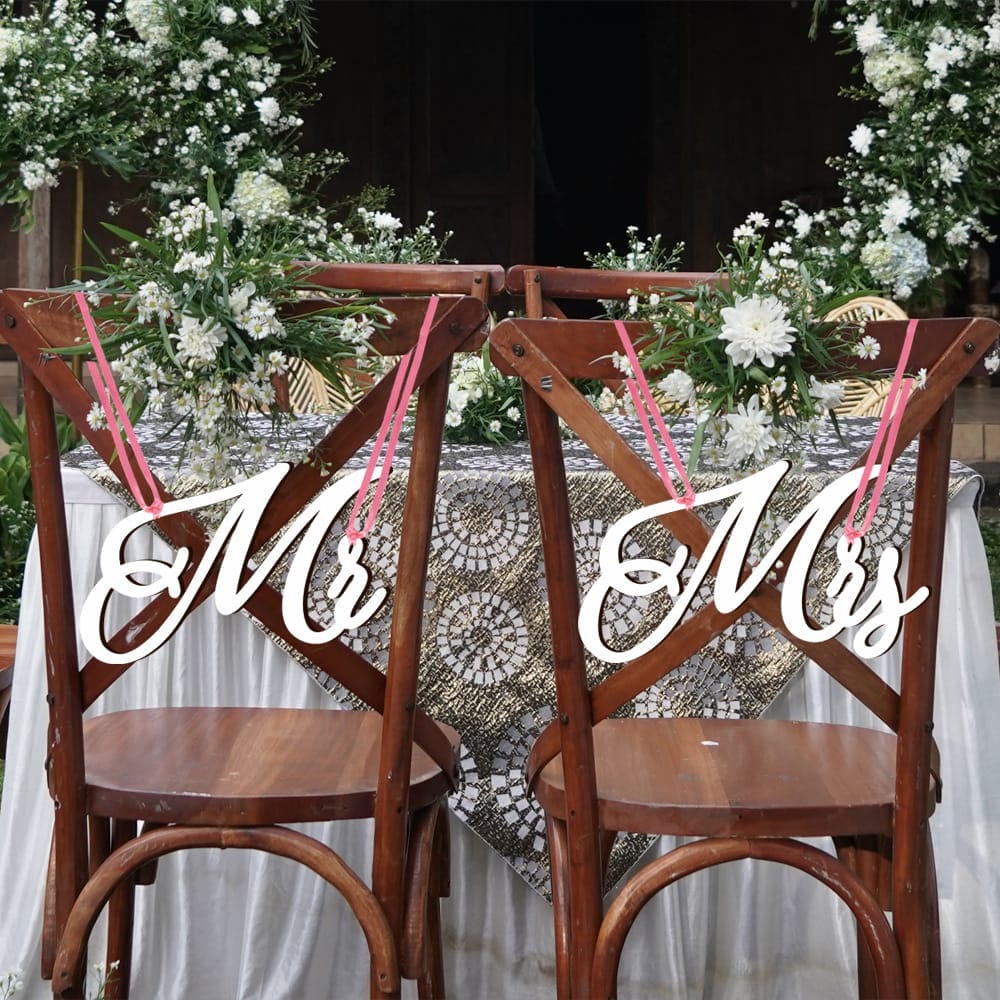 Wooden wedding chair signs reading "Mr" & "Mrs," adorned with flowers.