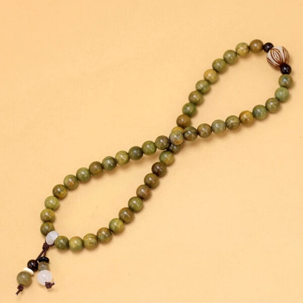 Green wooden bead bracelet with decorative accents. Wholesale beaded bracelets available.